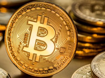 Shiny physical bitcoins on golden background. Blockchain technology.