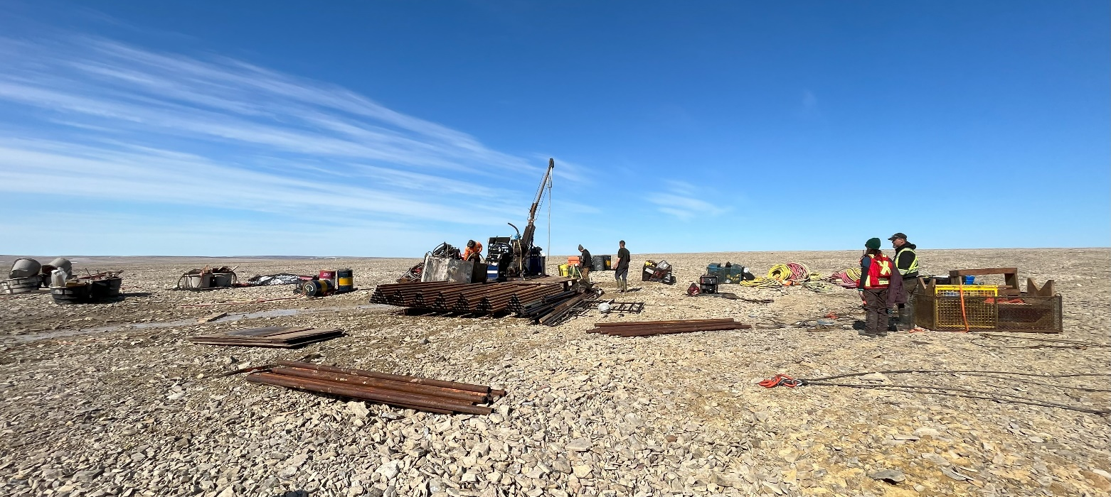 Bohrgerät und Crew auf Geröllfeld vor Blauem Himmel